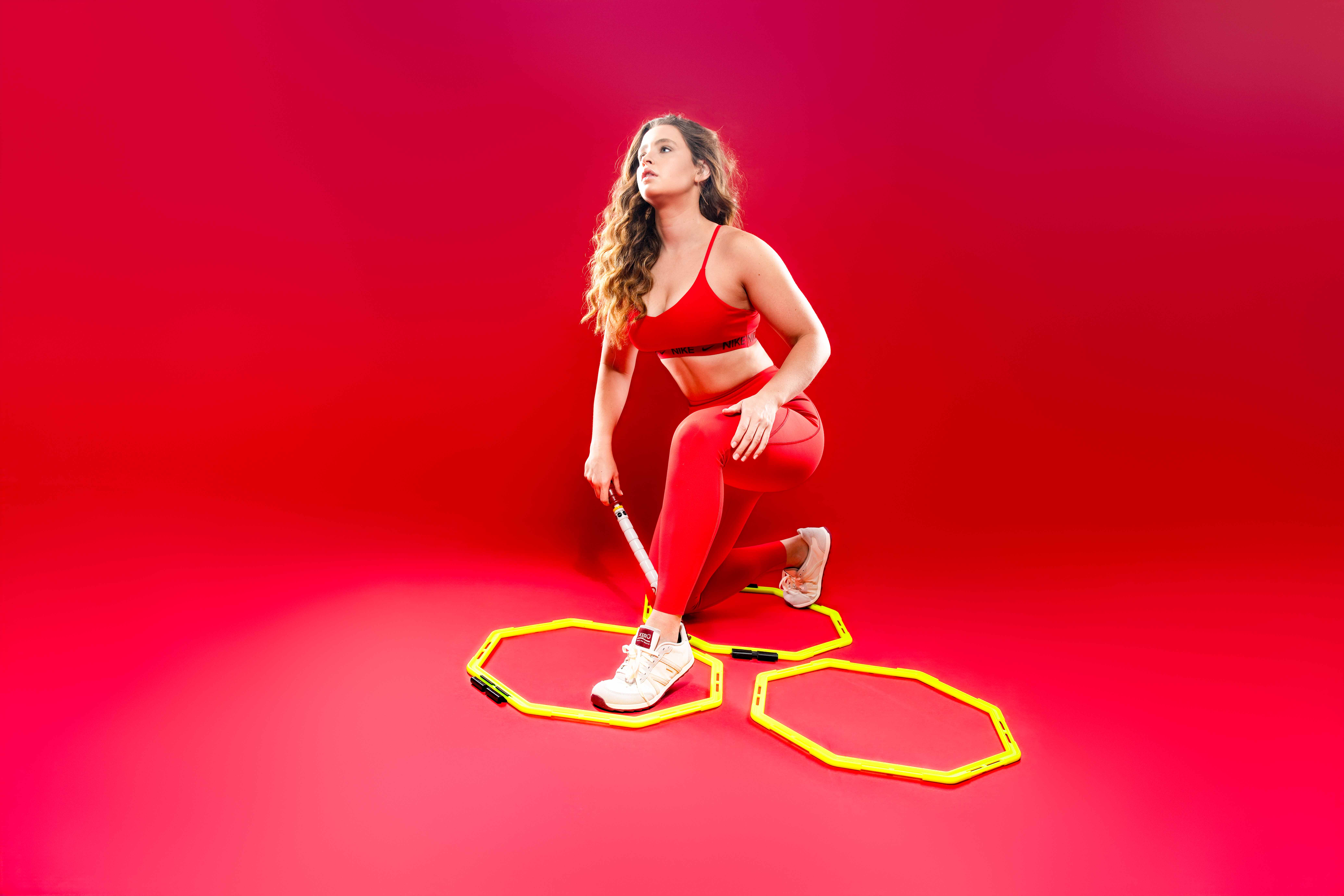 best washington dc physical therapist using the stick in a red nike fitness outfit and xero shoes kneeling in a toe tap drill ocagon