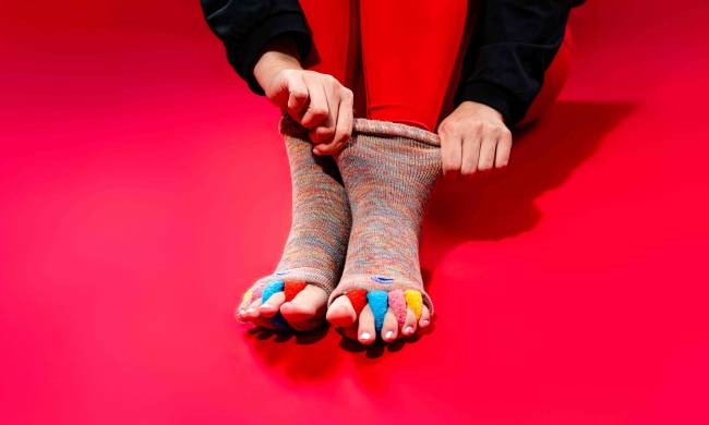 Close-up of red crew-style foot alignment socks with four integrated toe separators, used by Washington, D.C. physical therapists to improve foot mechanics and toe splay for patients.Blog or Service Page) "Red Original Foot Alignment Socks featured at Rose Physical Therapy; a professional-grade alternative to silicone spacers that uses fabric dividers to gently realign toes and alleviate plantar fasciitis and