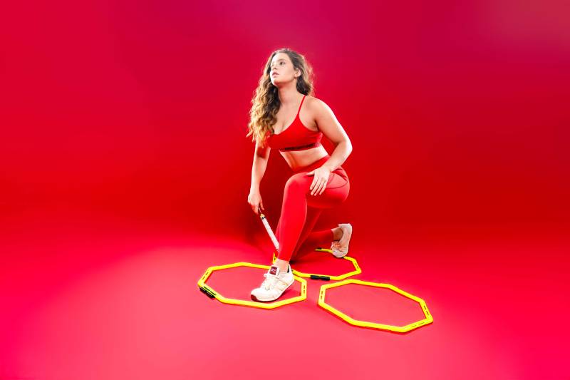 best washington dc physical therapist using the stick in a red nike fitness outfit and xero shoes kneeling in a toe tap drill ocagon
