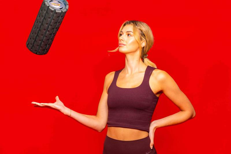 Doctors of physical therapy at Rose PT recommend the Brazyn collapsible foam roller for patients, shown here being used by a blonde athlete for post-workout recovery.
