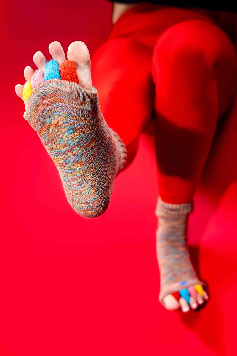 Therapeutic red socks with integrated toe dividers shown in a Rose Physical Therapy treatment room in D.C., highlighting a professional tool for correcting overlapping toes and improving foot posture.